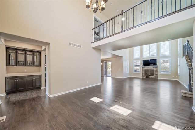 unfurnished living room with dark wood-type flooring, an inviting chandelier, and a high ceiling