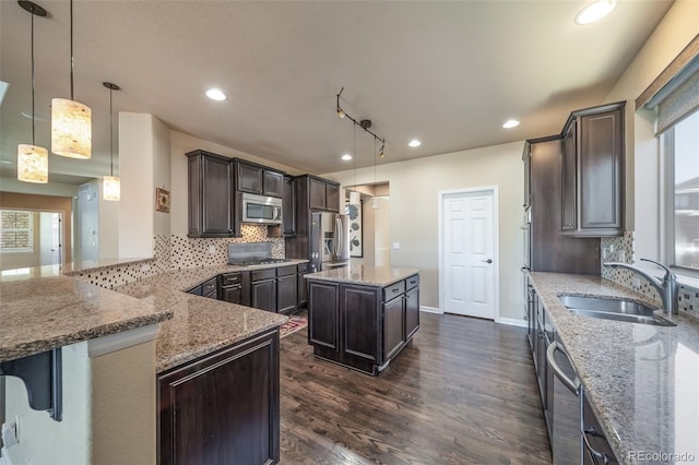 kitchen featuring stainless steel appliances, pendant lighting, a center island, and dark hardwood / wood-style flooring