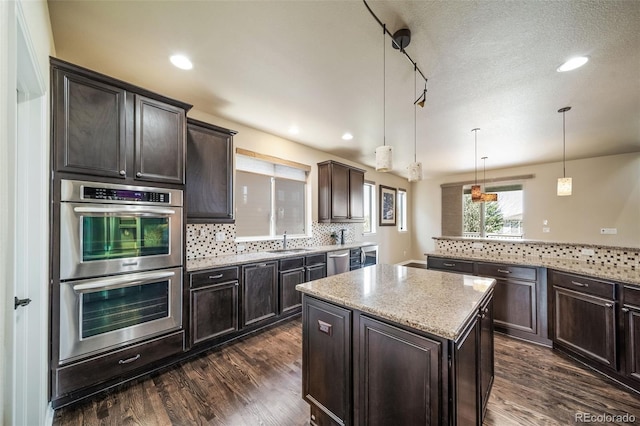 kitchen featuring stainless steel appliances, tasteful backsplash, dark wood-type flooring, and decorative light fixtures