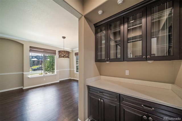 kitchen with light stone countertops, dark hardwood / wood-style floors, pendant lighting, and crown molding