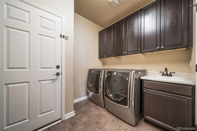 clothes washing area featuring cabinets, sink, light tile flooring, and washer and clothes dryer