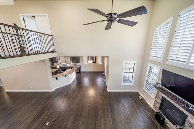 living room with dark hardwood / wood-style flooring, a high ceiling, and ceiling fan