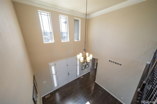 entryway featuring ornamental molding, a chandelier, and dark wood-type flooring