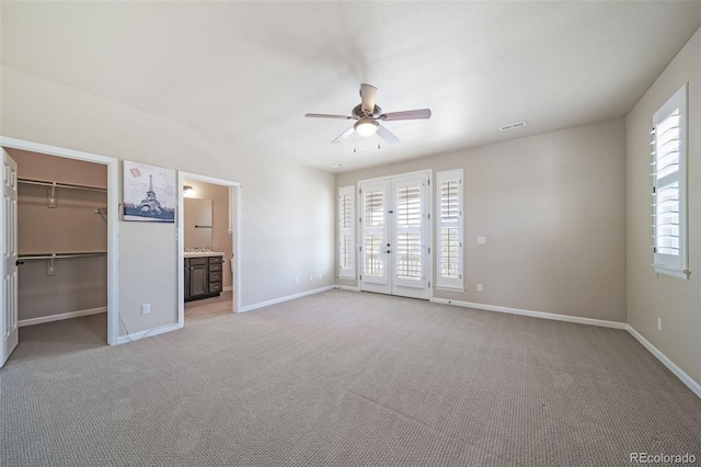 unfurnished bedroom with ensuite bathroom, ceiling fan, carpet flooring, a closet, and a walk in closet