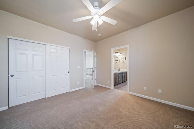 unfurnished bedroom featuring a closet, ceiling fan, ensuite bathroom, and carpet flooring