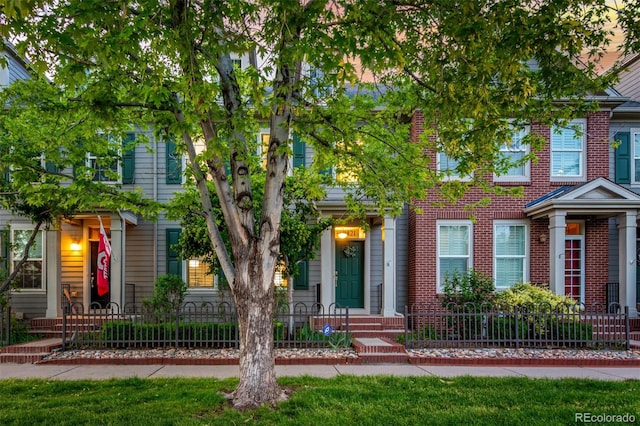townhome / multi-family property with a fenced front yard and brick siding