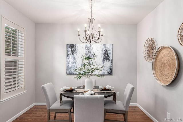 dining space featuring a chandelier, dark wood finished floors, and baseboards