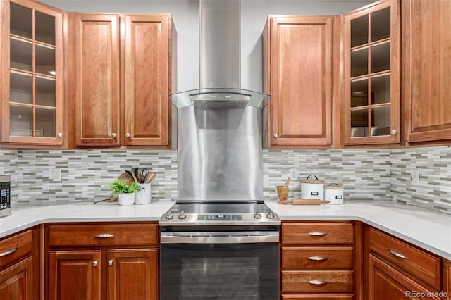 kitchen featuring range hood, appliances with stainless steel finishes, light countertops, backsplash, and glass insert cabinets