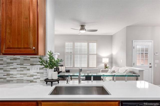 kitchen featuring a sink, a ceiling fan, backsplash, light countertops, and dishwasher