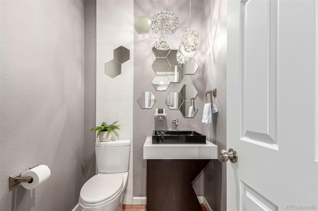 bathroom featuring toilet, vanity, and baseboards