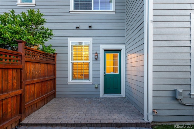 property entrance with fence and a patio area