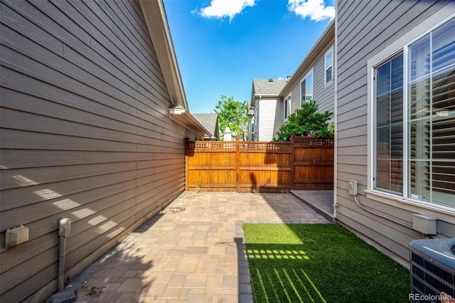 view of home's exterior with central AC, fence, and a patio