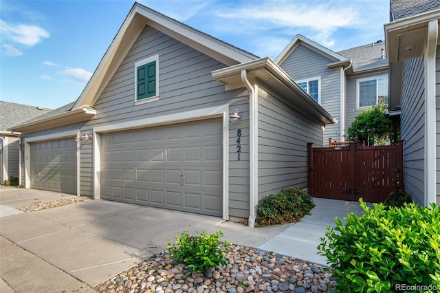 view of home's exterior featuring concrete driveway, fence, and an attached garage