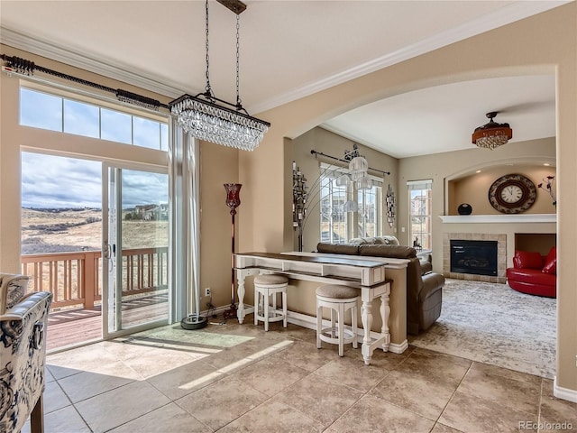 tiled dining space with a fireplace, a chandelier, and ornamental molding