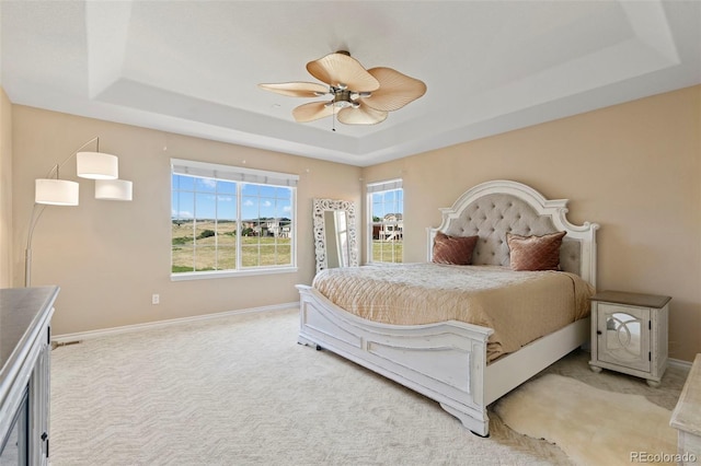 bedroom featuring a raised ceiling, ceiling fan, and carpet flooring