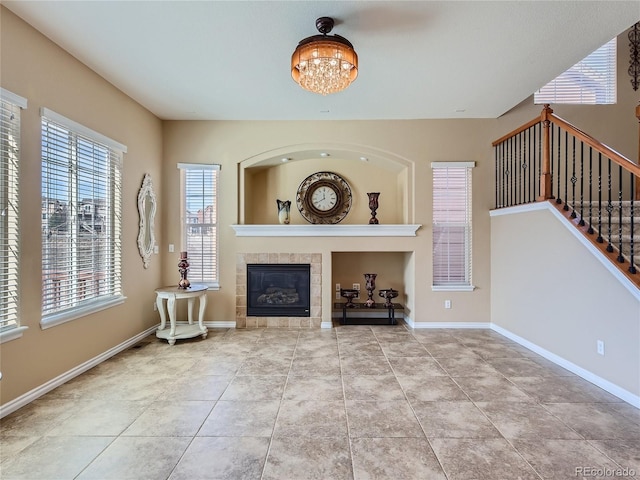 unfurnished living room featuring light tile patterned floors, a tile fireplace, and an inviting chandelier