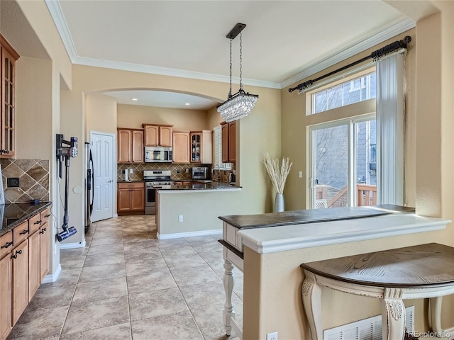 kitchen with decorative backsplash, a kitchen bar, crown molding, and appliances with stainless steel finishes