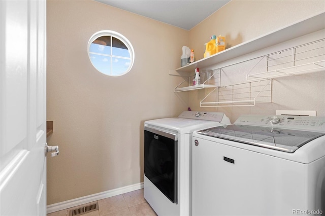 clothes washing area with light tile patterned floors and washer and dryer