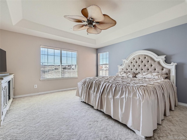 bedroom with light carpet, a raised ceiling, and ceiling fan