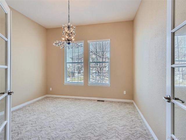 carpeted spare room featuring an inviting chandelier and a wealth of natural light