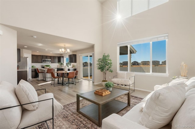 living room featuring a notable chandelier, light hardwood / wood-style flooring, and a high ceiling