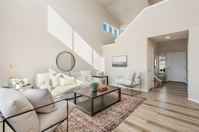 living room featuring high vaulted ceiling and light hardwood / wood-style flooring