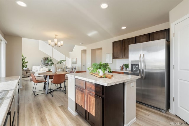 kitchen featuring light wood-type flooring, a center island, stainless steel refrigerator with ice dispenser, dark brown cabinets, and an inviting chandelier