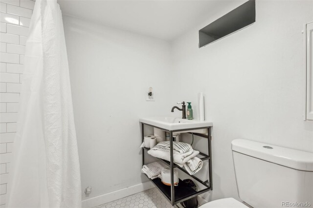 full bathroom featuring toilet, a sink, a shower with shower curtain, and baseboards