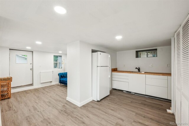 kitchen with freestanding refrigerator, radiator, light wood-style floors, recessed lighting, and baseboards
