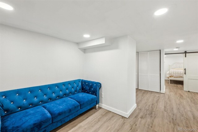living area with wood finished floors, baseboards, recessed lighting, and a barn door