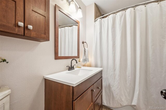 full bathroom featuring vanity, toilet, curtained shower, and a textured wall