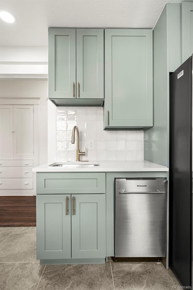 kitchen with dishwasher, green cabinets, black refrigerator, decorative backsplash, and sink