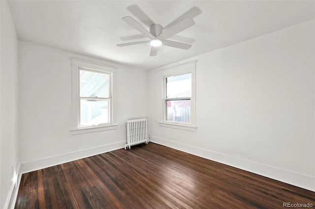 spare room featuring dark wood-type flooring, ceiling fan, and radiator heating unit