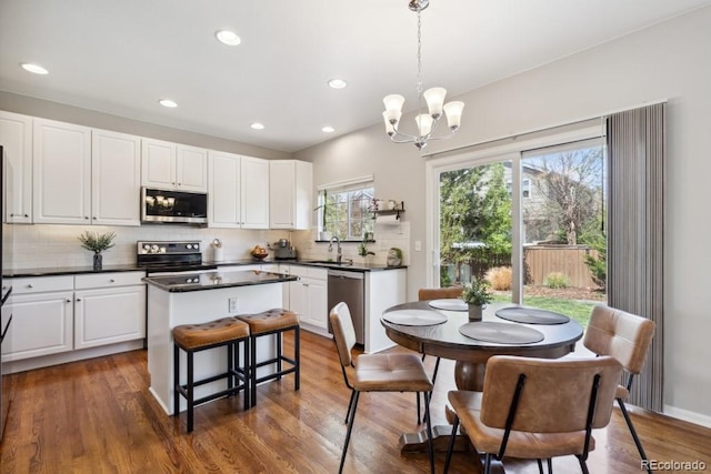 kitchen featuring dark countertops, a center island, white cabinets, tasteful backsplash, and stainless steel appliances