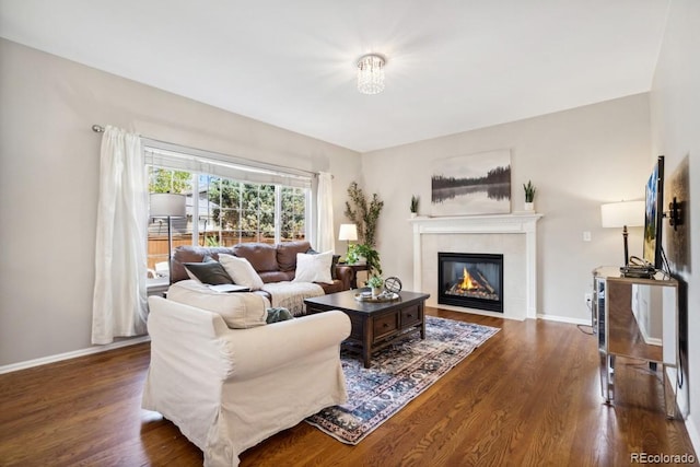 living room with baseboards, dark wood-style floors, and a tile fireplace