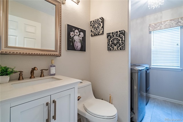 bathroom with washing machine and clothes dryer, toilet, and vanity