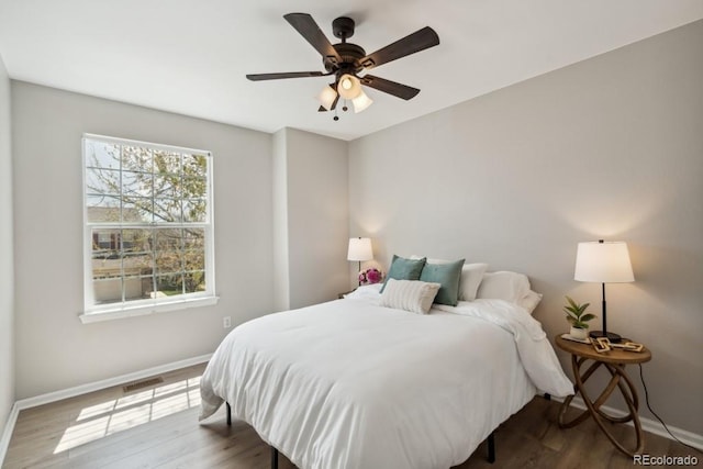 bedroom with ceiling fan, baseboards, visible vents, and wood finished floors