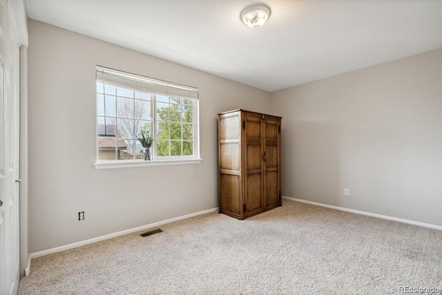 spare room featuring baseboards, visible vents, and carpet