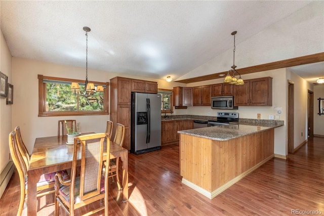 kitchen featuring stainless steel appliances, a chandelier, a peninsula, wood finished floors, and pendant lighting