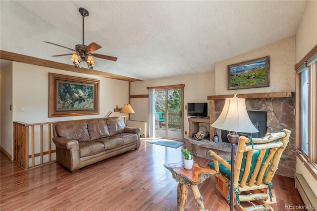 living room featuring a textured ceiling, a baseboard heating unit, a ceiling fan, wood finished floors, and a fireplace