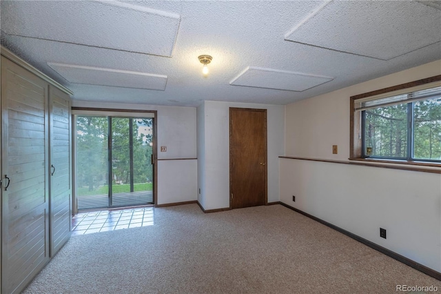 empty room featuring healthy amount of natural light, carpet flooring, a textured ceiling, and baseboards