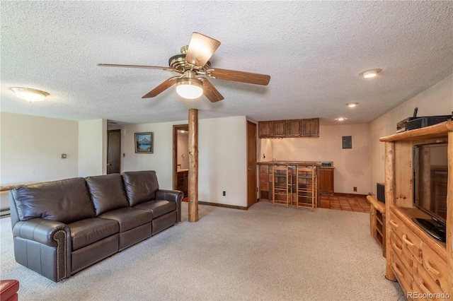 living room featuring light colored carpet, bar area, a textured ceiling, a ceiling fan, and baseboards