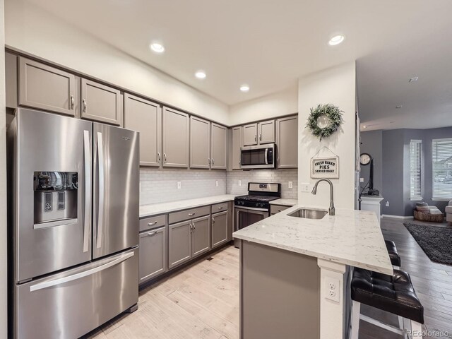 3921 E 141st Ave, Thornton, CO 80602 - kitchen featuring appliances with stainless steel finishes, gray cabinets, a sink, light wood-type flooring, and a peninsula