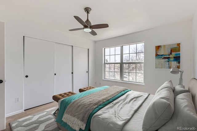 bedroom with a closet, a ceiling fan, and light wood-style flooring