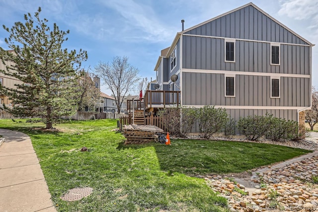 view of side of home featuring stairs, board and batten siding, a wooden deck, and a yard