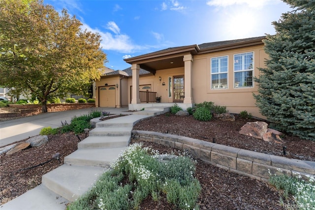 view of front of property with a garage, stucco siding, concrete driveway, and covered porch