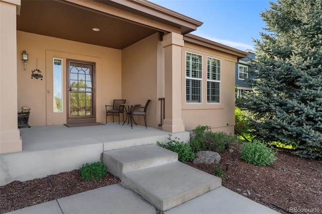 view of exterior entry featuring stucco siding and a porch