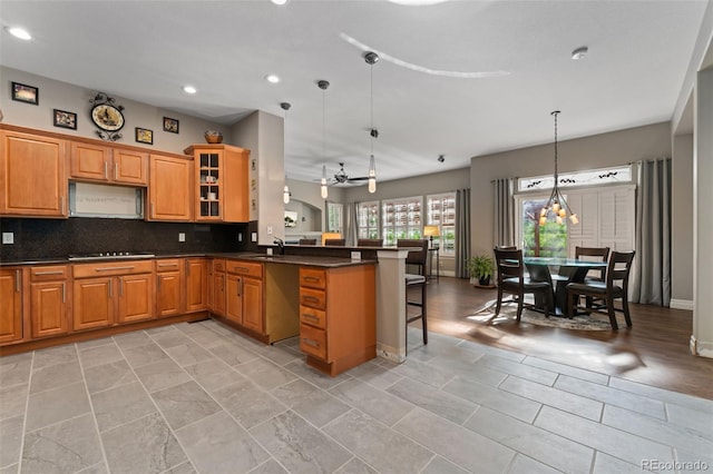 kitchen featuring a peninsula, a breakfast bar area, dark countertops, recessed lighting, and a ceiling fan