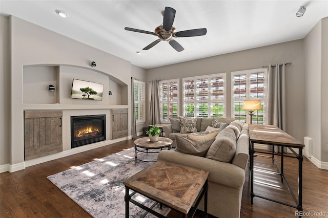 living room with a glass covered fireplace, baseboards, ceiling fan, wood finished floors, and recessed lighting