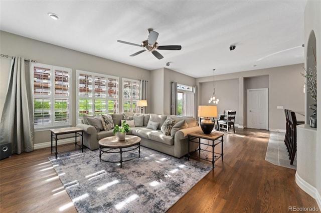 living room featuring dark wood finished floors, a ceiling fan, baseboards, and a chandelier